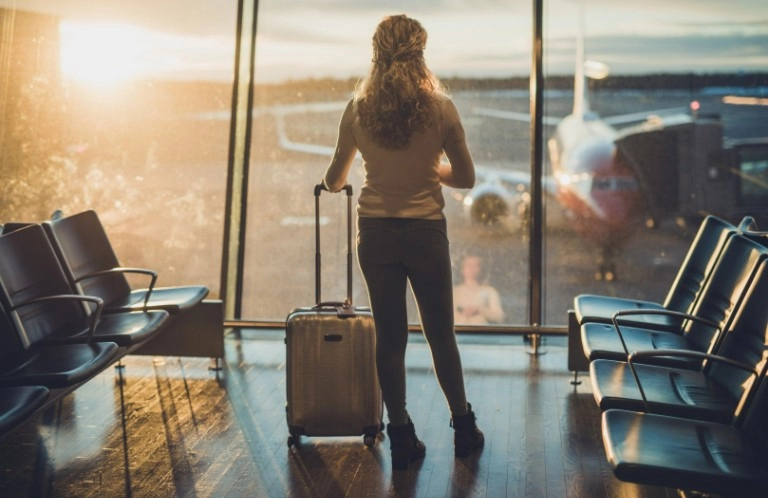 kobieta z walizką patrzy na samolot